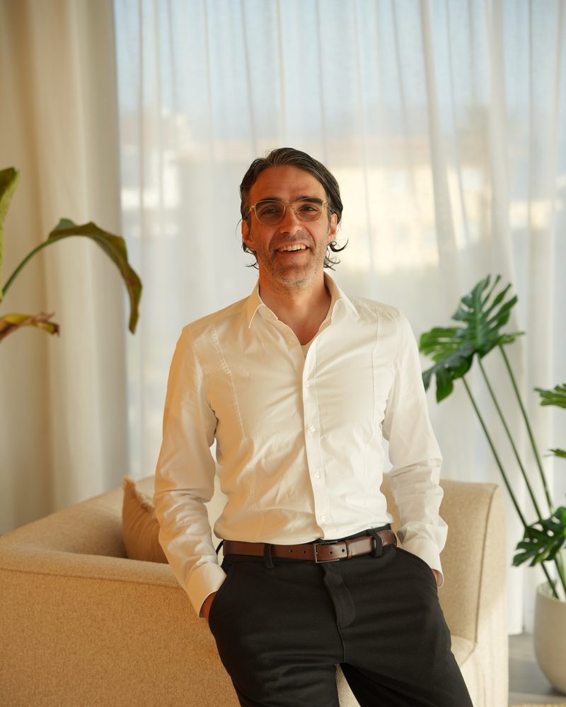 Nicco Krezdorn laughing, leaning on a sofa